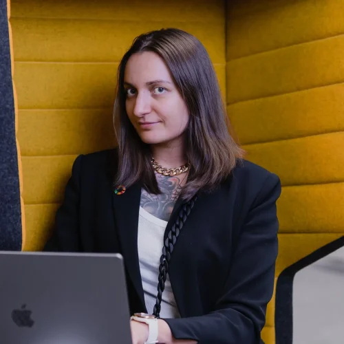 Naishenkilö istuu nojatuolilla kannettavan kanssa.